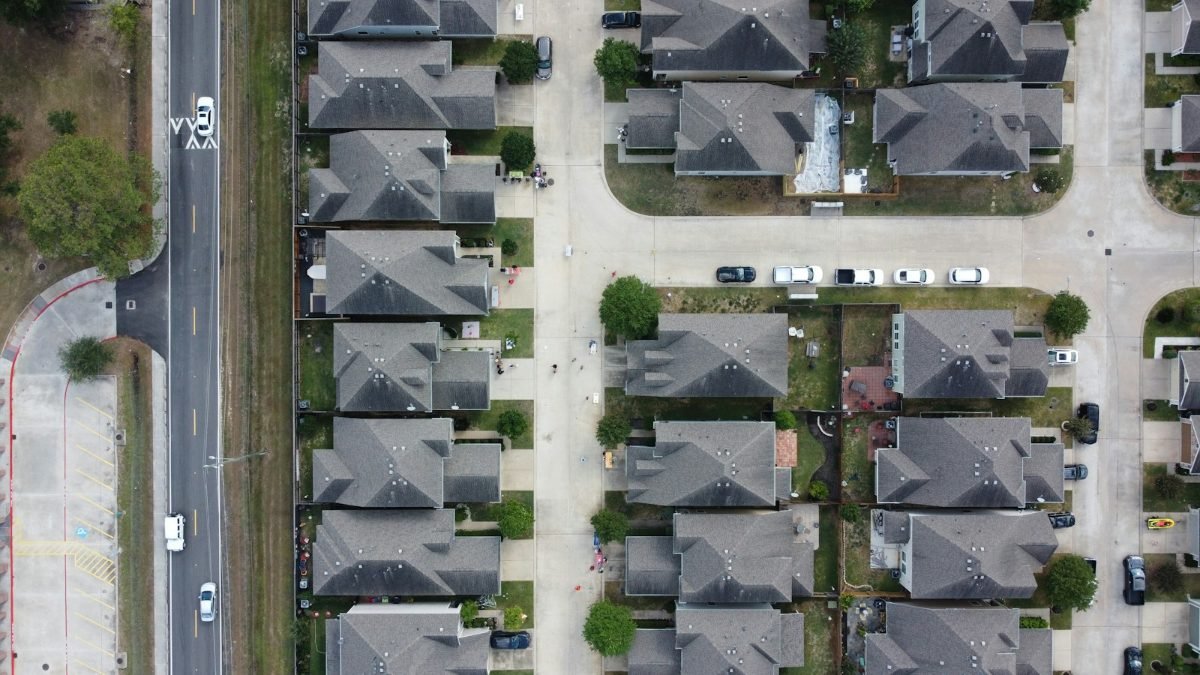 Aerial view of rows of gray shingle roofs in a subdivision
