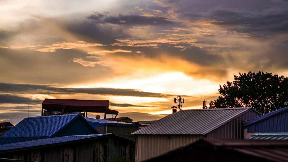 Metal roofs on low buildings under a golden sunset sky