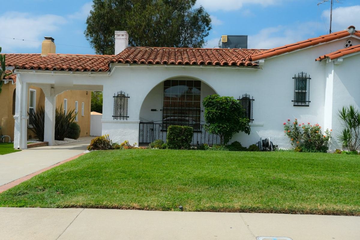 A white stucco house with a red clay tile roof and an arched porch